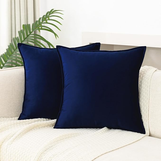 A pair of elegant navy blue velvet throw pillows resting on a neutral-colored couch, complementing a soft knitted throw. no-save